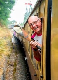 Ovacome trustee Richard leaning out of a train carrying the Commonwealth Games baton